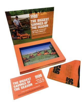 An open box with some promotional materials inside. The Scag logo and the words 'The biggest savings of the season' are printed on the bottom of the lid over a photo of a man riding a Scag lawn mower.